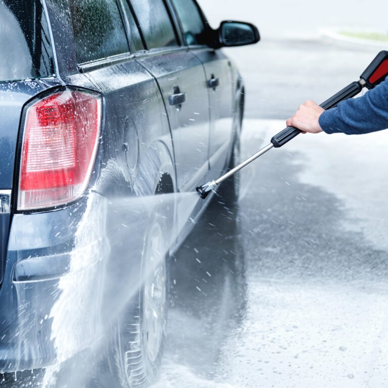 Professional car wash worker is washing client's car